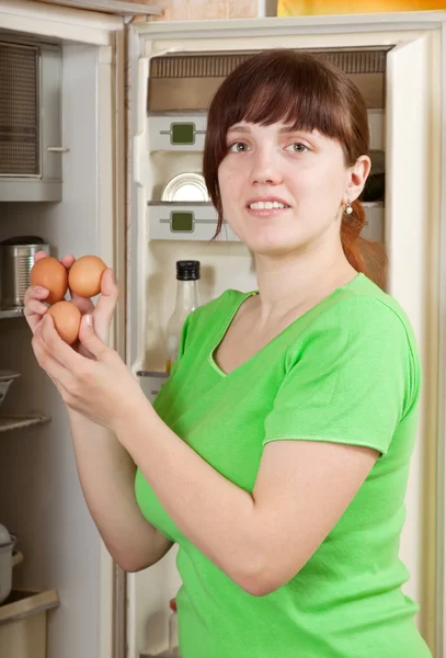 Mujer poniendo huevos frescos en la nevera — Foto de Stock