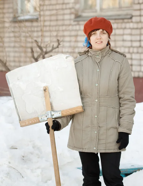 Vrouw met schop in besneeuwde straat — Stockfoto