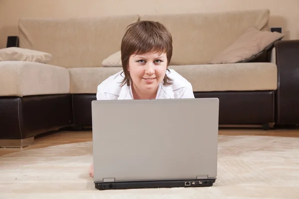 Жінка лежить на підлозі і використовує ноутбук — стокове фото