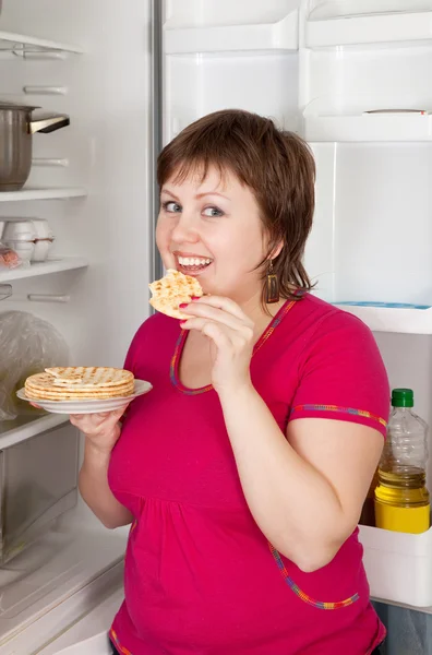 Γυναίκα τρώει πίτα από το ψυγείο — Φωτογραφία Αρχείου