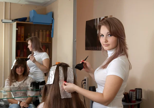 Стилист раскрашивает волосы девушки — стоковое фото