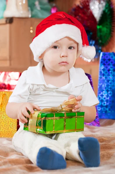 クリスマスの贈り物と一緒に座っている男の子 — ストック写真