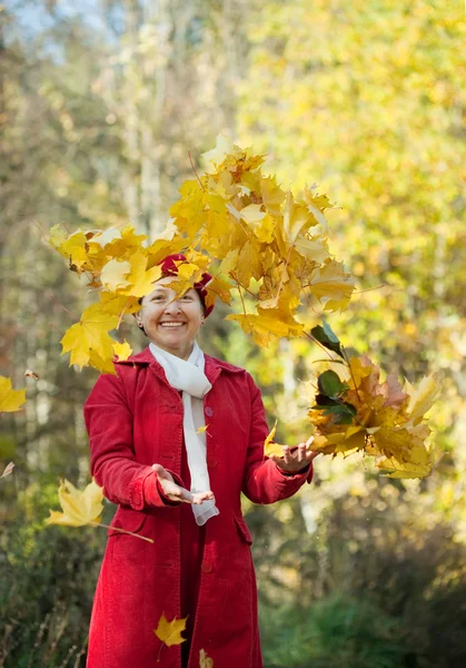 Ευτυχής ώριμη γυναίκα που ρίχνουν τα κίτρινα φύλλα — Φωτογραφία Αρχείου
