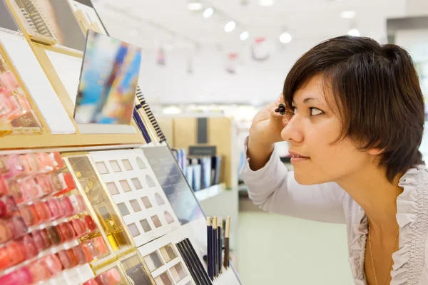 Woman chooses mascara at cosmetics shop Royalty Free Stock Images