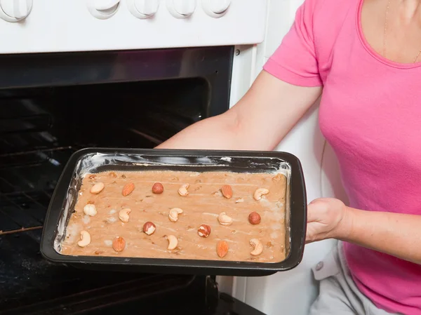 Kobiece ręce umieszcza ciasto w piekarniku — Zdjęcie stockowe