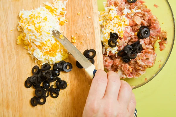 Adds grated eggs and sliced olives in mince — Stock Photo, Image