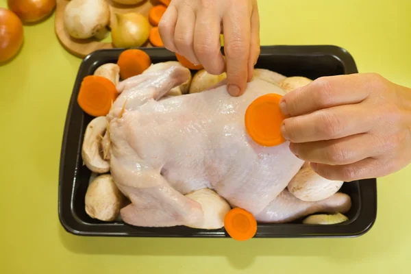 Female hands adds carrot to chicken — Stock Photo, Image