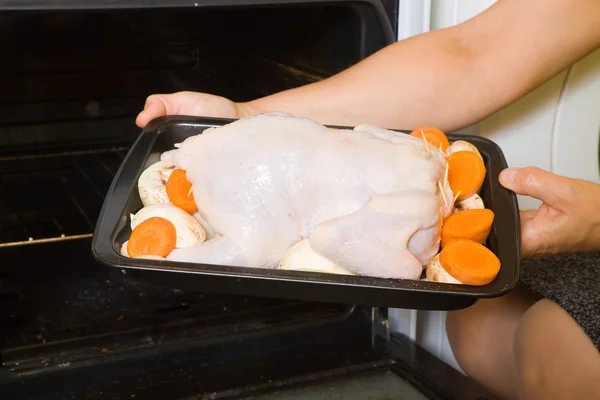Mãos a pôr frango no forno — Fotografia de Stock