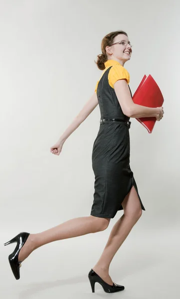 Giovane bella donna corre con una cartella rossa in mano — Foto Stock