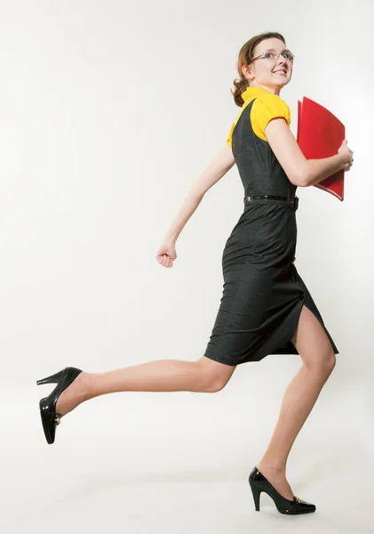 Joven hermosa mujer corre con una carpeta roja en las manos — Foto de Stock