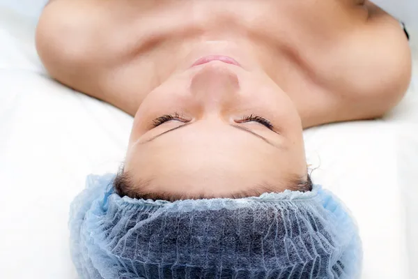 Jeune femme caucasienne couchée recevant un massage de la tête Image En Vente