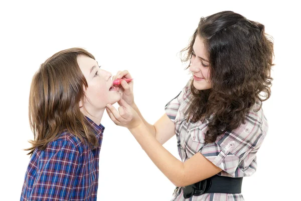 Senior girl dyes younger lip by pomade — Stock Photo, Image