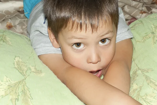 Egy kisfiú fekszik az ágyon. — Stock Fotó