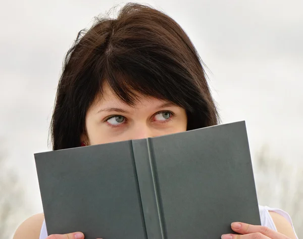 Woman peeking over edge of book — Stock Photo, Image