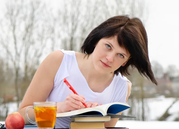 Ung kvinna med böcker och te — Stockfoto