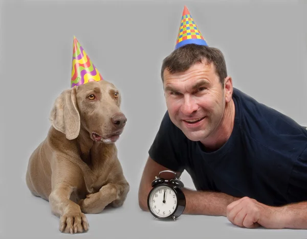 The man and dog lie in celebratory hats — Stock Photo, Image