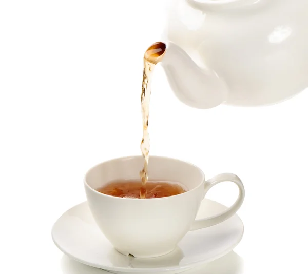 Té que se vierte en una taza de té aislada sobre un fondo blanco — Foto de Stock