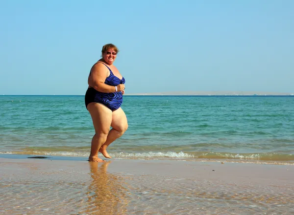 Übergewichtige Frau läuft am Strand — Stockfoto