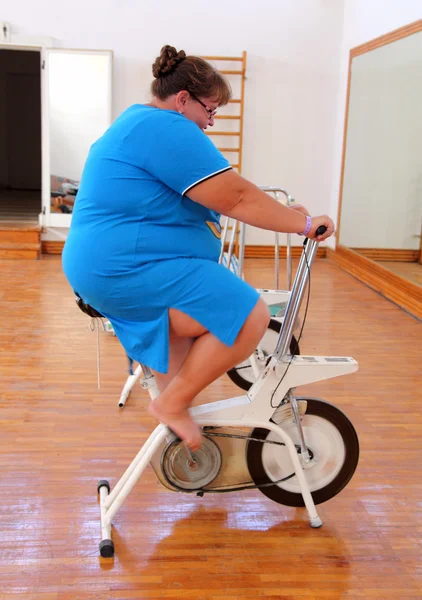 Mujer con sobrepeso haciendo ejercicio en bicicleta — Foto de Stock