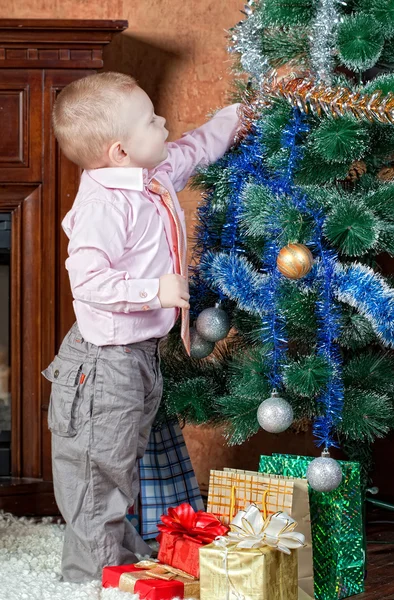 Little boy dresses up a Christmas fur-tree