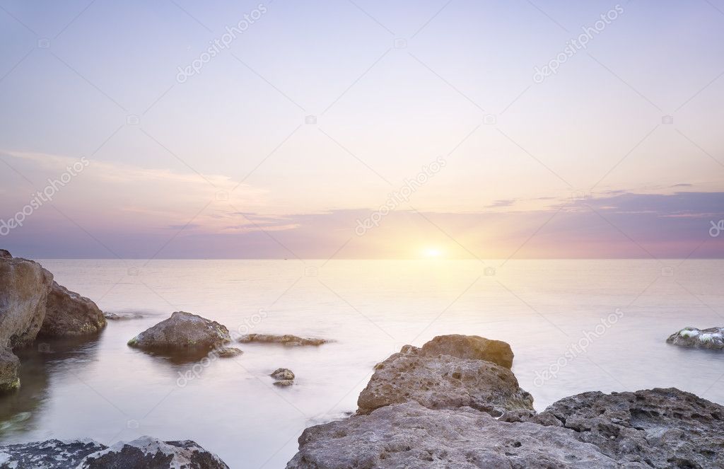Rock in ocean on sunset.