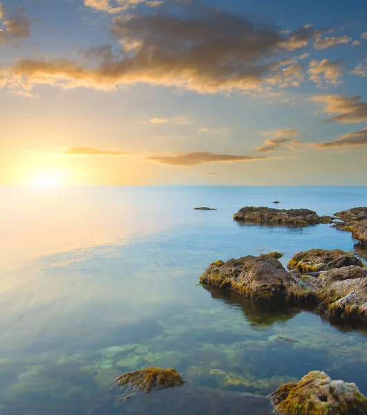 Rock in zee op zonsondergang. — Stockfoto
