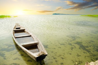 Boat at coast against a sunset clipart