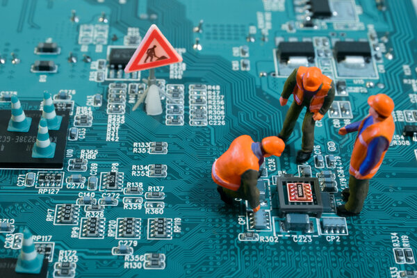 Miniature engineers fixing error on chip of motherboard