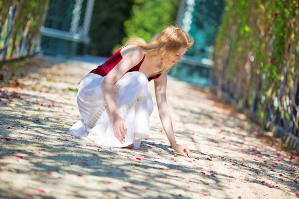Young woman picking up petals — Stock Photo, Image