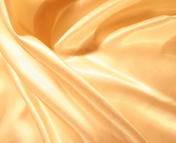 Гладкий элегантный золотой атлас в качестве фона — стоковое фото
