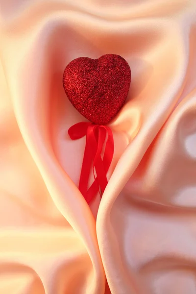 Červené srdce na elegantní růžové hedvábí pro den svatého Valentýna pozadí — Stock fotografie