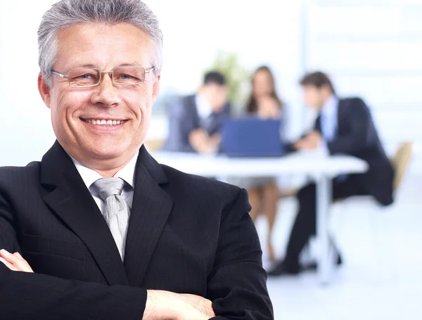 Успешный бизнесмен, стоящий со своим персоналом на заднем плане в офисе — стоковое фото