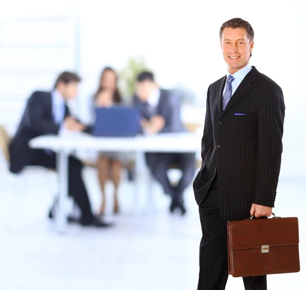 Erfolgreicher Geschäftsmann steht mit seinen Mitarbeitern im Hintergrund im Büro — Stockfoto
