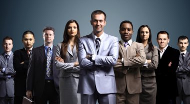 Business team formed of young businessmen standing over a dark background clipart