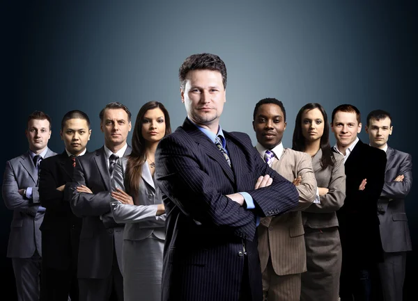 ビジネス チームは、暗い背景の上に立っている若いビジネスマンの形成 — ストック写真