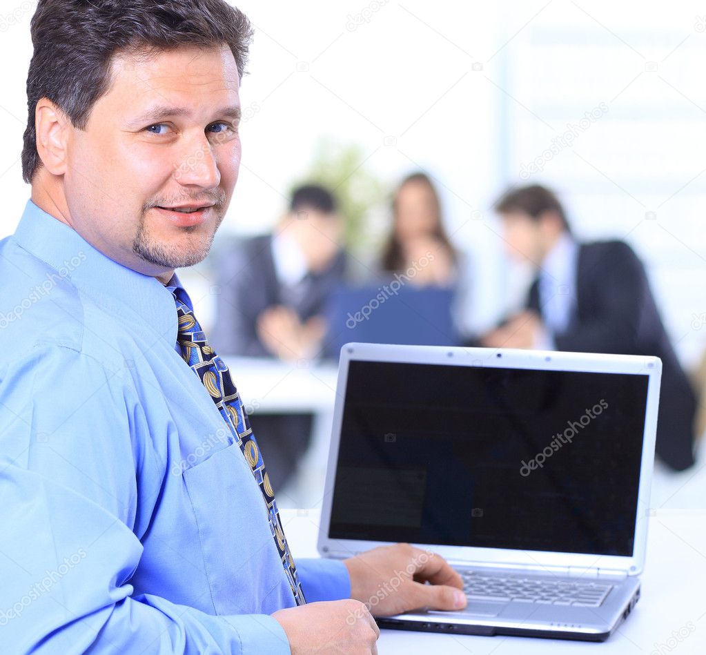 Portrait of a happy man entrepreneur displaying computer laptop in office