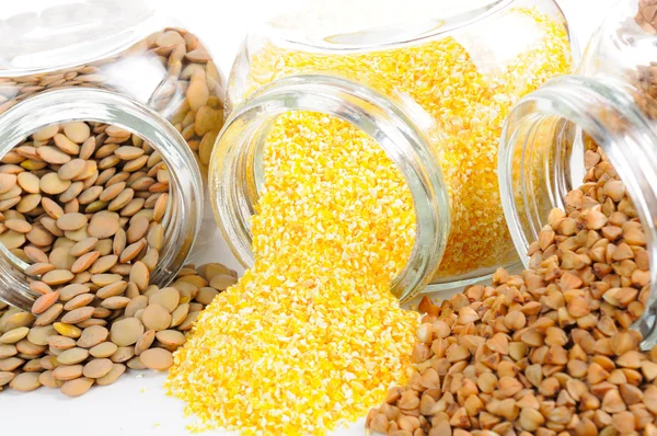 Frascos de vidro com lentilhas, grãos de milho e trigo mourisco — Fotografia de Stock