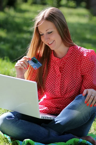 Chica joven con un ordenador portátil y una tarjeta de crédito — Foto de Stock