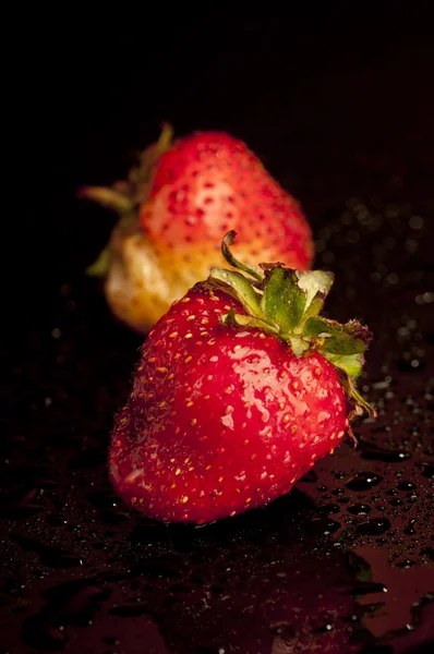 Röda färska jordgubbar på mörk bakgrund med vatten droppar — Stockfoto