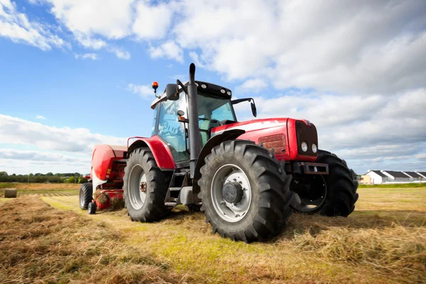 Tractor collecting haystack in the field, panning technique Stock Image