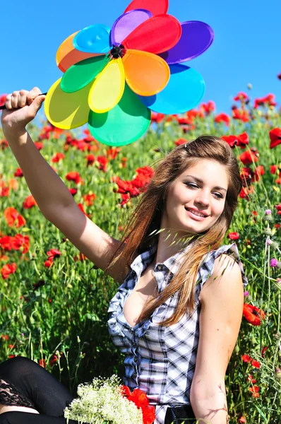 Chica con molino de viento en el campo de amapola —  Fotos de Stock