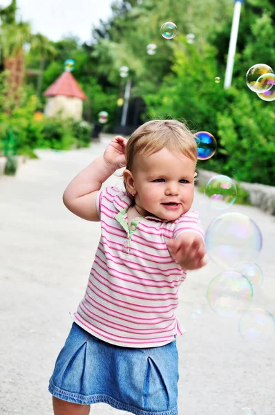Дитяча дівчинка ловить мильні бульбашки — стокове фото