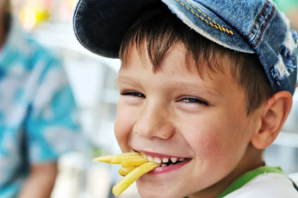 Мальчик ест картошку фри — стоковое фото