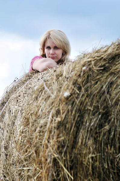 Молодая женщина и огромный стог сена — стоковое фото