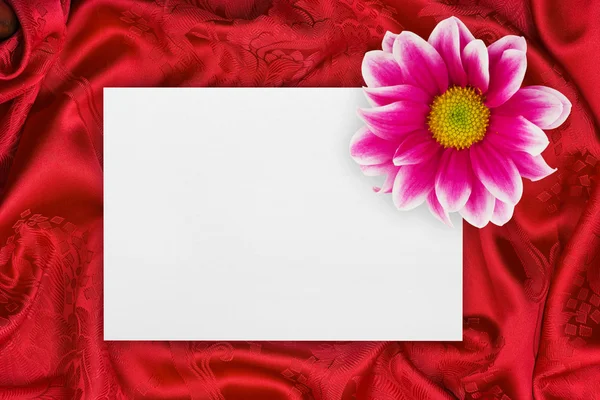 Grußkarte und Blume auf rotem Tuch — Stockfoto