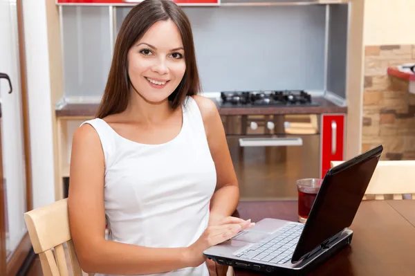 女人用的笔记本电脑是在厨房里 — 图库照片