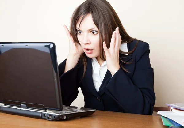 Przerażona kobieta patrzy na ekran laptopa. — Zdjęcie stockowe