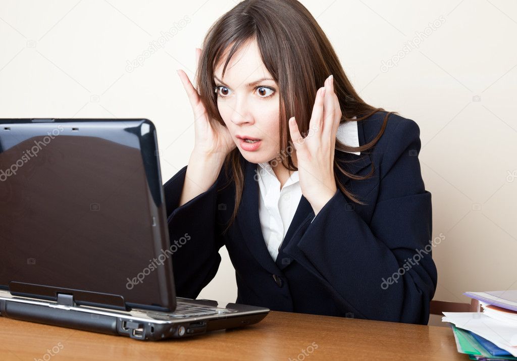 Frightened woman is looking at the laptop screen