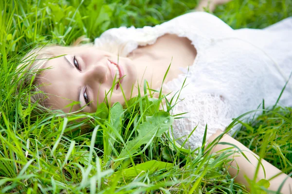 Menina bonita está deitada na grama verde — Fotografia de Stock