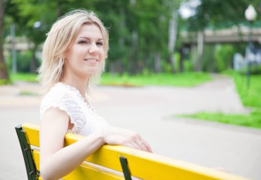 kadın parkta sarı bankta oturuyor